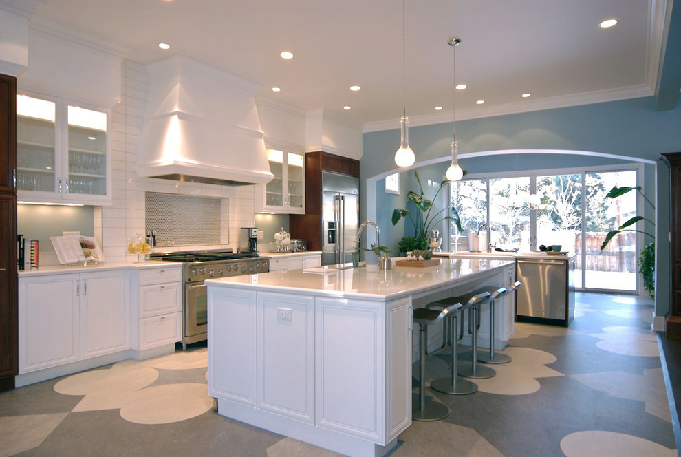 This is an example of a traditional kitchen in Denver with stainless steel appliances, white cabinets, white splashback, subway tile splashback, multi-coloured floor and recessed-panel cabinets.