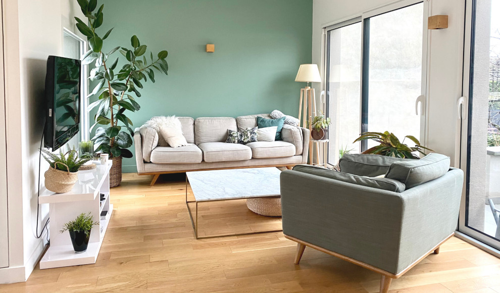 Ejemplo de salón abierto tradicional renovado de tamaño medio sin chimenea con paredes verdes, suelo de madera clara, televisor independiente, suelo beige y papel pintado