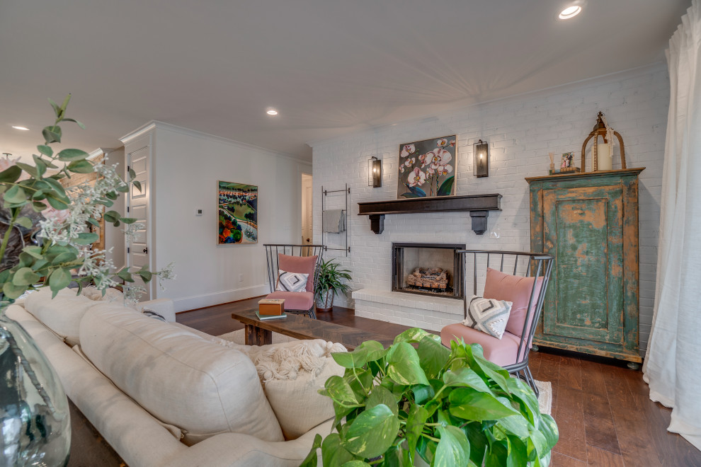 This is an example of a country open concept family room in Richmond with white walls, laminate floors, a standard fireplace, a brick fireplace surround, no tv and brown floor.