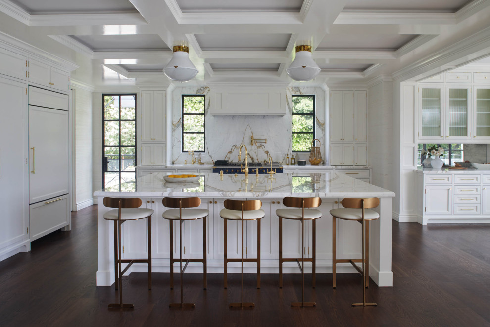 This is an example of a classic open plan kitchen in Los Angeles with white cabinets, white splashback, integrated appliances, dark hardwood flooring, an island, brown floors, white worktops and a coffered ceiling.
