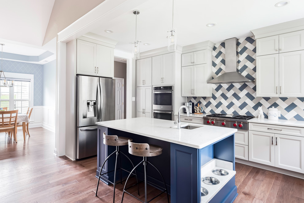 Kitchen - transitional light wood floor kitchen idea in Charlotte with an undermount sink, recessed-panel cabinets, multicolored backsplash, stainless steel appliances, an island, white countertops and gray cabinets