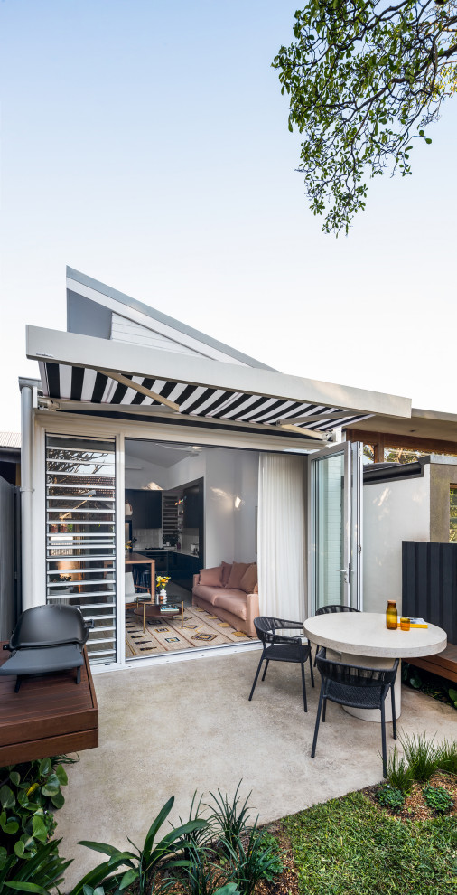 This is an example of a small and white contemporary bungalow brick detached house in Sydney with a metal roof and a grey roof.
