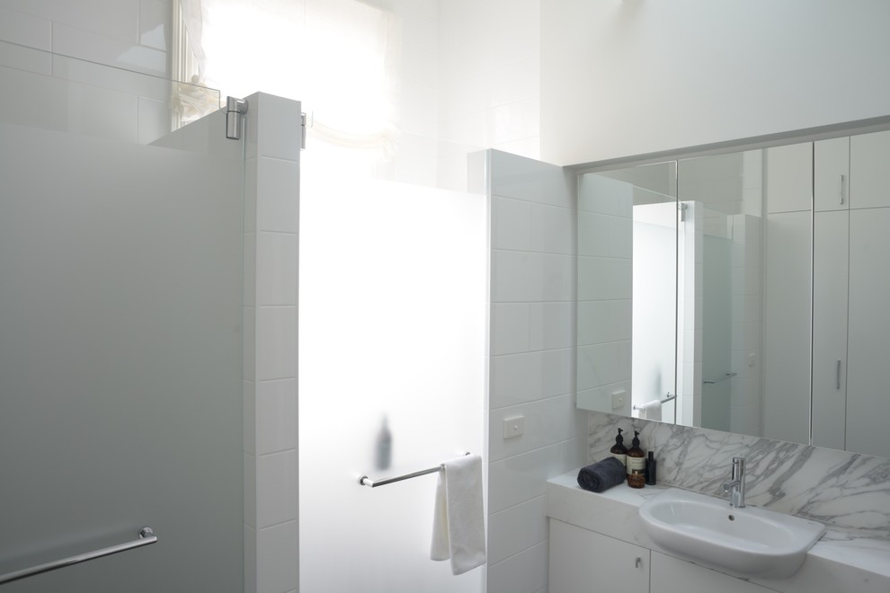Design ideas for a small contemporary bathroom in Melbourne with a one-piece toilet, white tile, ceramic tile, white walls, porcelain floors, marble benchtops, a hinged shower door and grey benchtops.