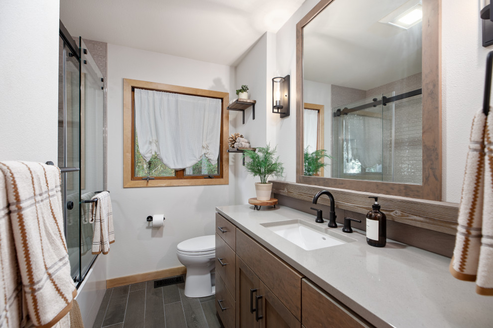 Small mountain style 3/4 gray tile and ceramic tile porcelain tile, gray floor and single-sink bathroom photo in Portland with flat-panel cabinets, medium tone wood cabinets, a one-piece toilet, gray walls, a drop-in sink, quartz countertops, gray countertops and a built-in vanity