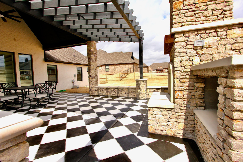 This is an example of a mid-sized backyard patio in Oklahoma City with with fireplace, stamped concrete and a pergola.