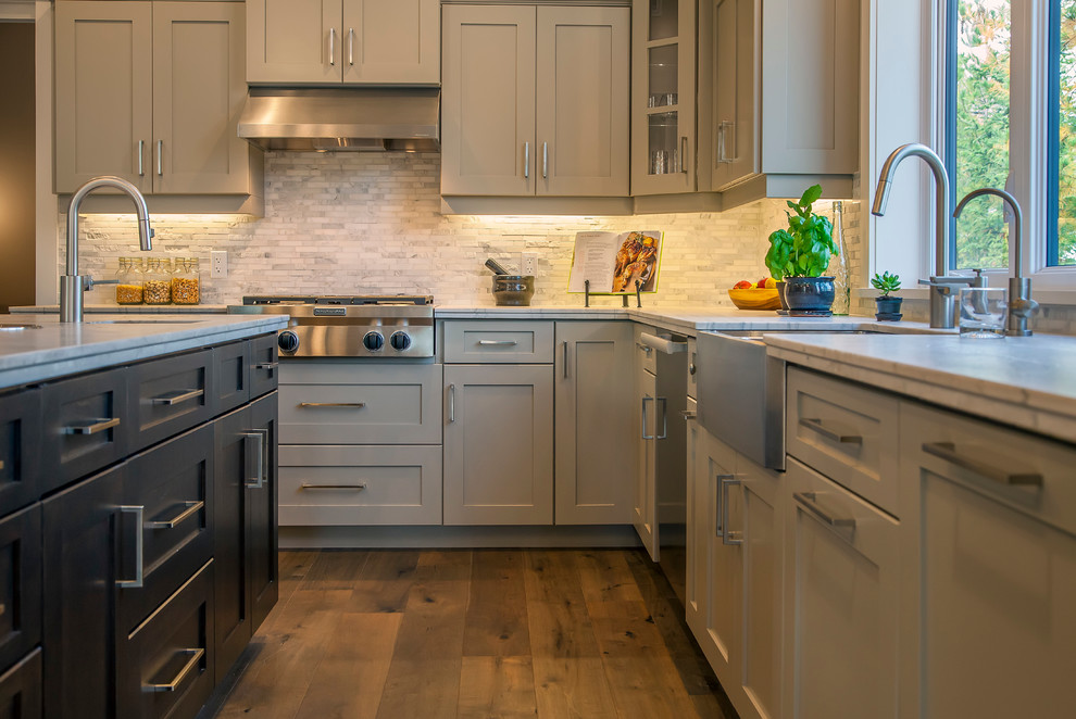 This is an example of a large arts and crafts u-shaped eat-in kitchen in Toronto with a farmhouse sink, shaker cabinets, grey cabinets, granite benchtops, white splashback, stone tile splashback, stainless steel appliances, dark hardwood floors and with island.