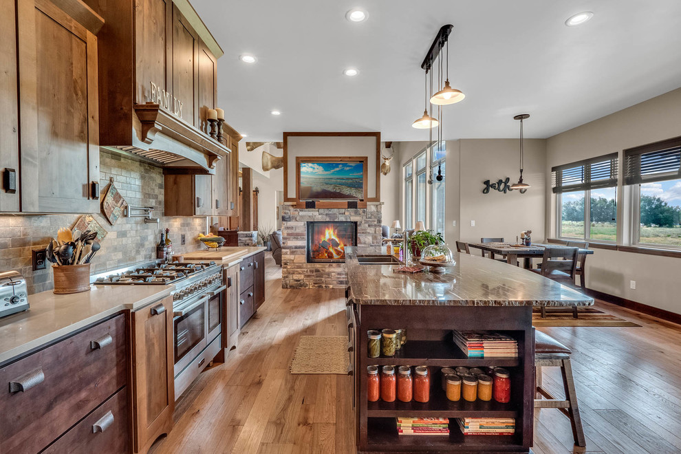 Mid-sized country galley kitchen in Denver with an undermount sink, dark wood cabinets, granite benchtops, stone tile splashback, stainless steel appliances, medium hardwood floors, with island, shaker cabinets, brown splashback, brown floor and brown benchtop.