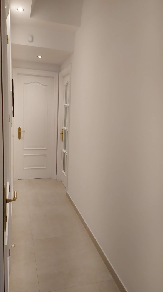На фото: коридор: освещение в стиле неоклассика (современная классика) с белыми стенами, полом из керамической плитки и бежевым полом с