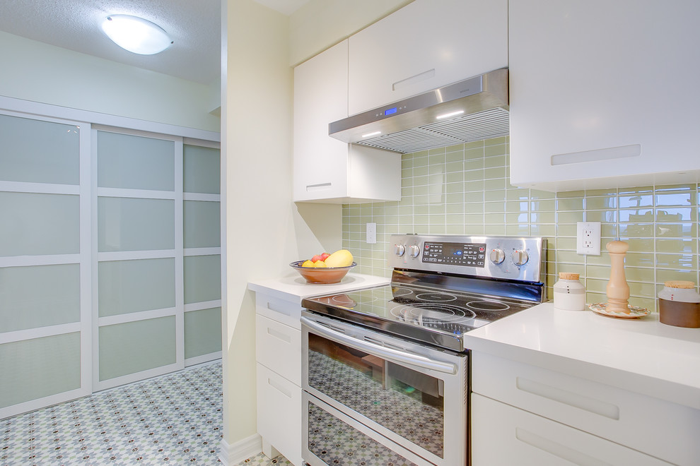 Photo of a small contemporary galley kitchen pantry in Toronto with an undermount sink, flat-panel cabinets, white cabinets, quartzite benchtops, green splashback, cement tiles, a peninsula, multi-coloured floor, glass tile splashback, stainless steel appliances and white benchtop.