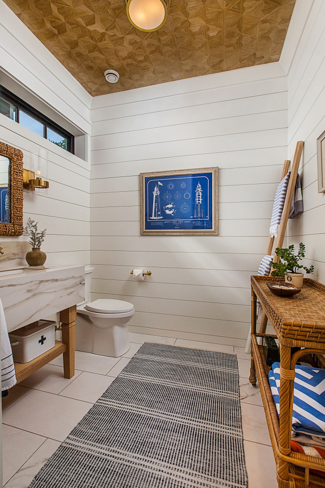 Modelo de cuarto de baño único y de pie costero de tamaño medio con paredes blancas, suelo de baldosas de cerámica, madera, machihembrado, encimera de ónix y suelo blanco