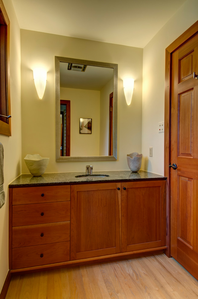 Inspiration for a mid-sized arts and crafts 3/4 bathroom in Denver with shaker cabinets, dark wood cabinets, beige walls, light hardwood floors, an undermount sink and beige floor.