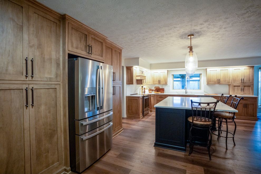 Inspiration for a large transitional l-shaped medium tone wood floor and brown floor eat-in kitchen remodel with a single-bowl sink, shaker cabinets, medium tone wood cabinets, quartz countertops, white backsplash, quartz backsplash, stainless steel appliances, an island and white countertops