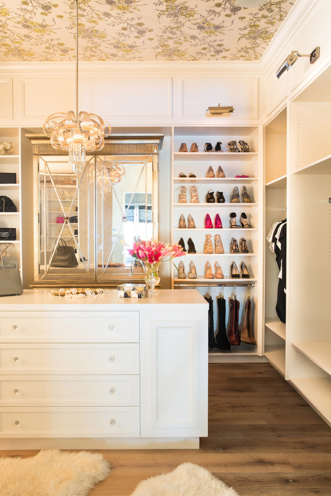 Design ideas for a transitional women's storage and wardrobe in Los Angeles with white cabinets and brown floor.