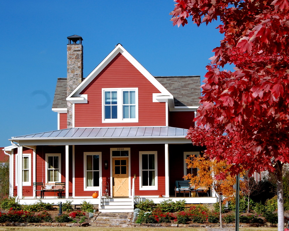 Photo of a mid-sized country two-storey red exterior in Little Rock with wood siding.