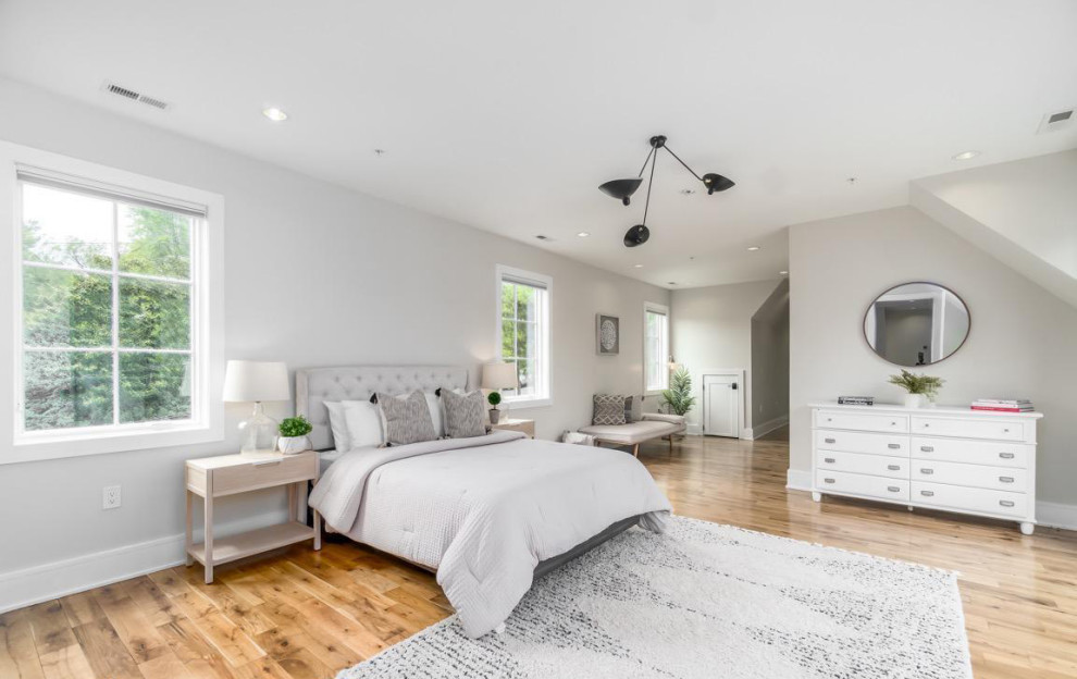 Immagine di una camera matrimoniale design con pareti bianche, parquet chiaro e pavimento marrone