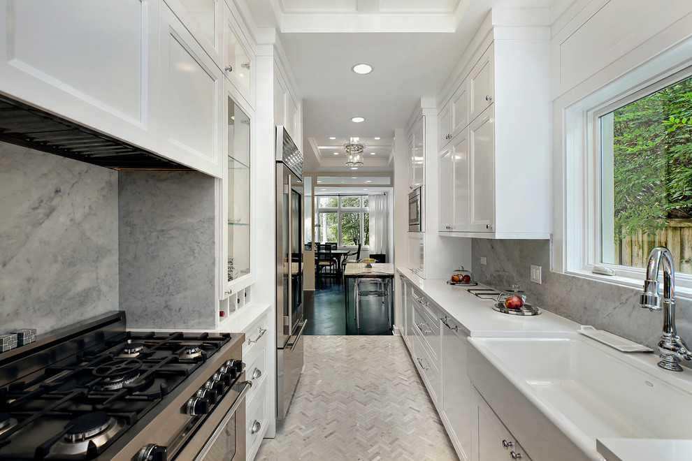Inspiration for a transitional galley separate kitchen in Chicago with a farmhouse sink, recessed-panel cabinets, white cabinets, grey splashback, stone slab splashback, stainless steel appliances and no island.