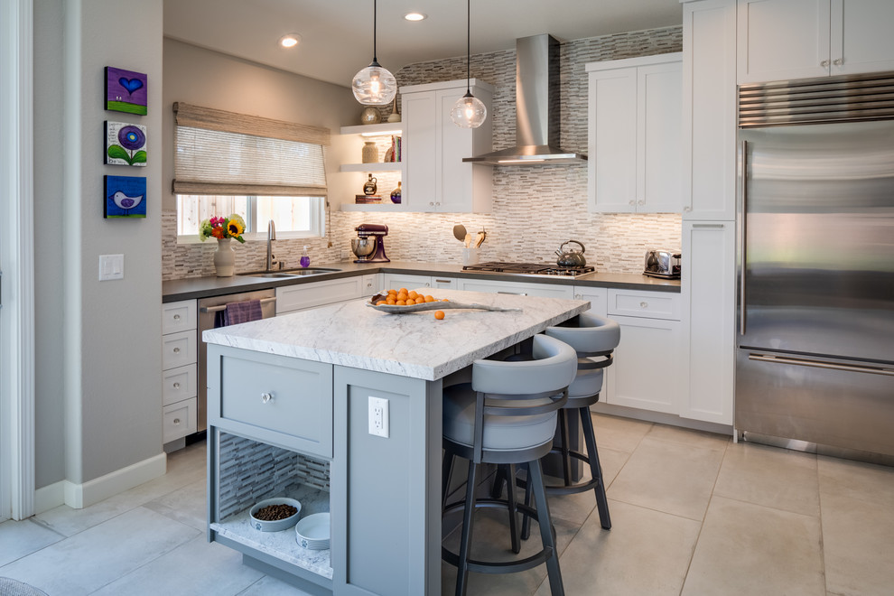 Mid-sized transitional l-shaped eat-in kitchen in San Diego with an undermount sink, recessed-panel cabinets, white cabinets, solid surface benchtops, matchstick tile splashback, stainless steel appliances, porcelain floors, with island, white benchtop, grey splashback and grey floor.