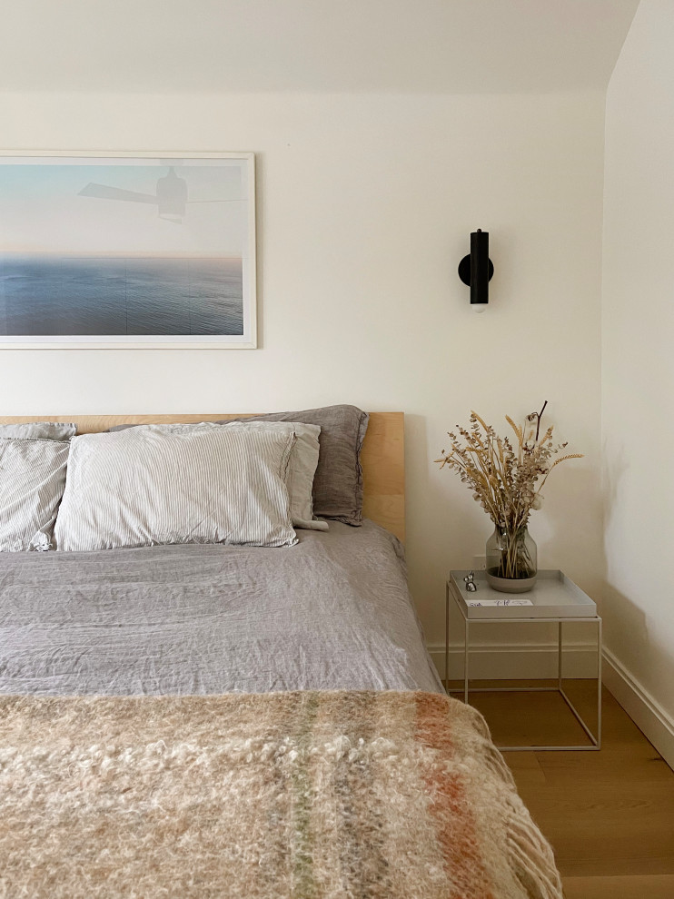 Example of a minimalist master light wood floor and brown floor bedroom design in Toronto with white walls