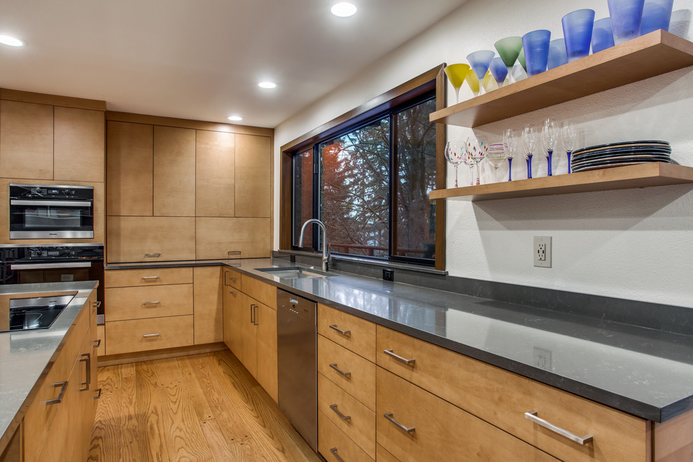 Mid-sized contemporary galley eat-in kitchen in Seattle with an undermount sink, flat-panel cabinets, light wood cabinets, quartz benchtops, white splashback, stainless steel appliances, medium hardwood floors, with island, brown floor and grey benchtop.