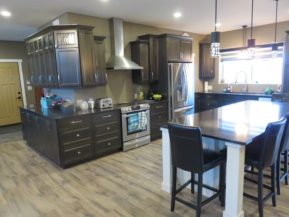 Example of a large transitional l-shaped light wood floor open concept kitchen design with gray cabinets, quartz countertops, stainless steel appliances, an island, a triple-bowl sink and shaker cabinets