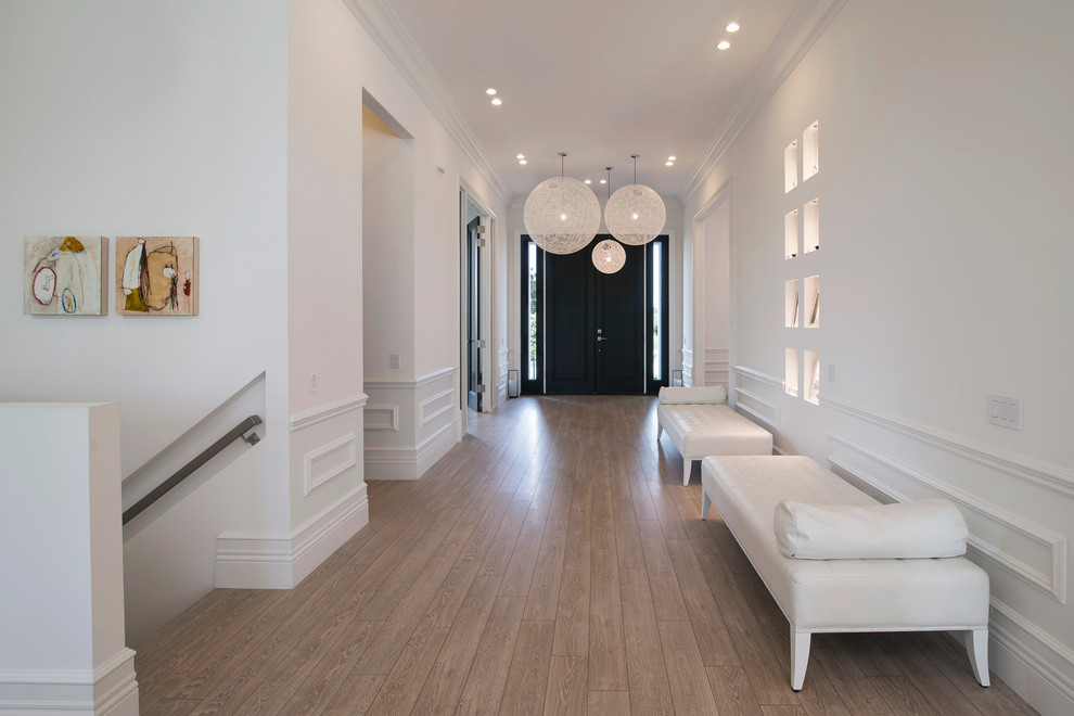 Photo of a large contemporary entry hall in DC Metro with white walls, light hardwood floors, a double front door and a black front door.