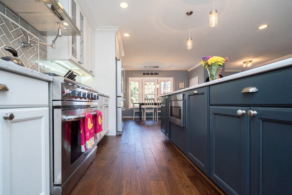Large transitional l-shaped dark wood floor and brown floor eat-in kitchen photo in DC Metro with a farmhouse sink, shaker cabinets, white cabinets, quartz countertops, gray backsplash, porcelain backsplash, stainless steel appliances and an island