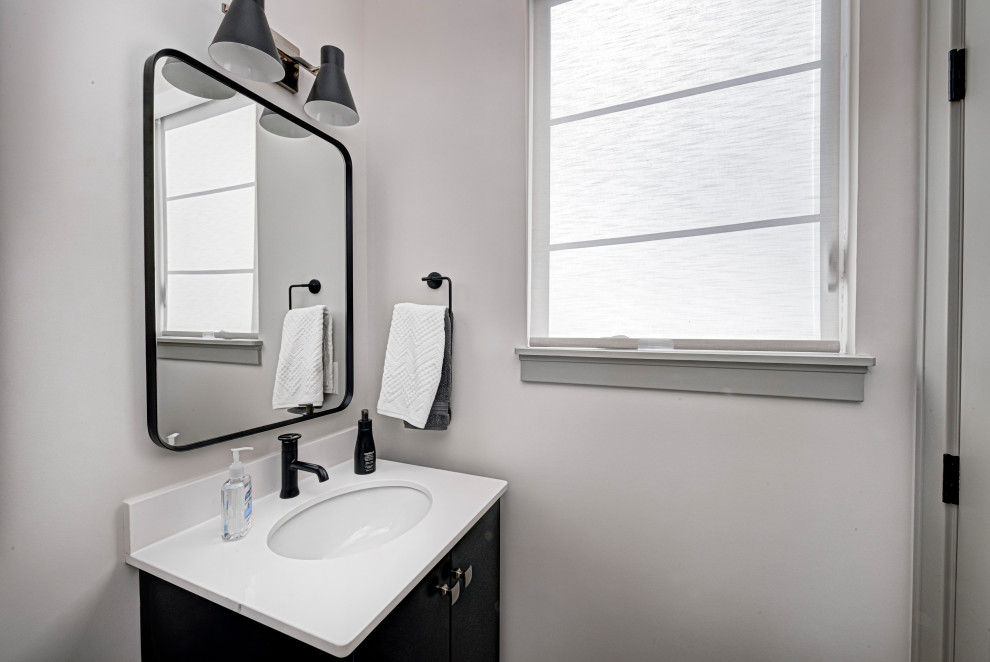 Inspiration for a mid-sized contemporary powder room in Indianapolis with flat-panel cabinets, black cabinets, an undermount sink, engineered quartz benchtops, white benchtops, a built-in vanity and white walls.