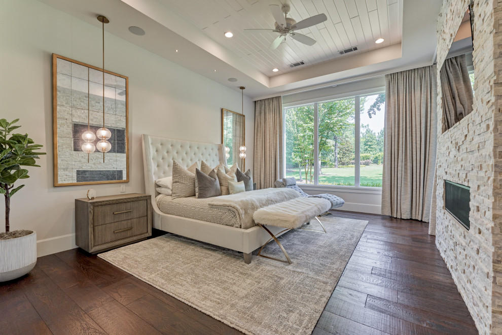 Example of a large transitional master dark wood floor, brown floor and shiplap ceiling bedroom design with white walls, a standard fireplace and a stone fireplace