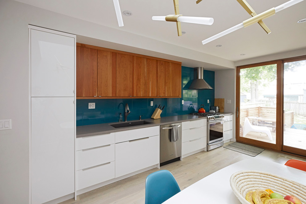 Photo of a mid-sized modern single-wall eat-in kitchen in Toronto with an undermount sink, flat-panel cabinets, white cabinets, quartz benchtops, blue splashback, ceramic splashback, stainless steel appliances, light hardwood floors, no island, beige floor and grey benchtop.