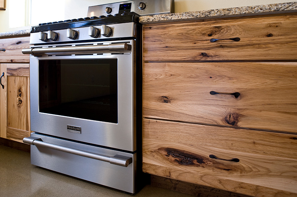 Eat-in kitchen - mid-sized rustic l-shaped concrete floor eat-in kitchen idea with an undermount sink, shaker cabinets, light wood cabinets, granite countertops, stainless steel appliances and an island