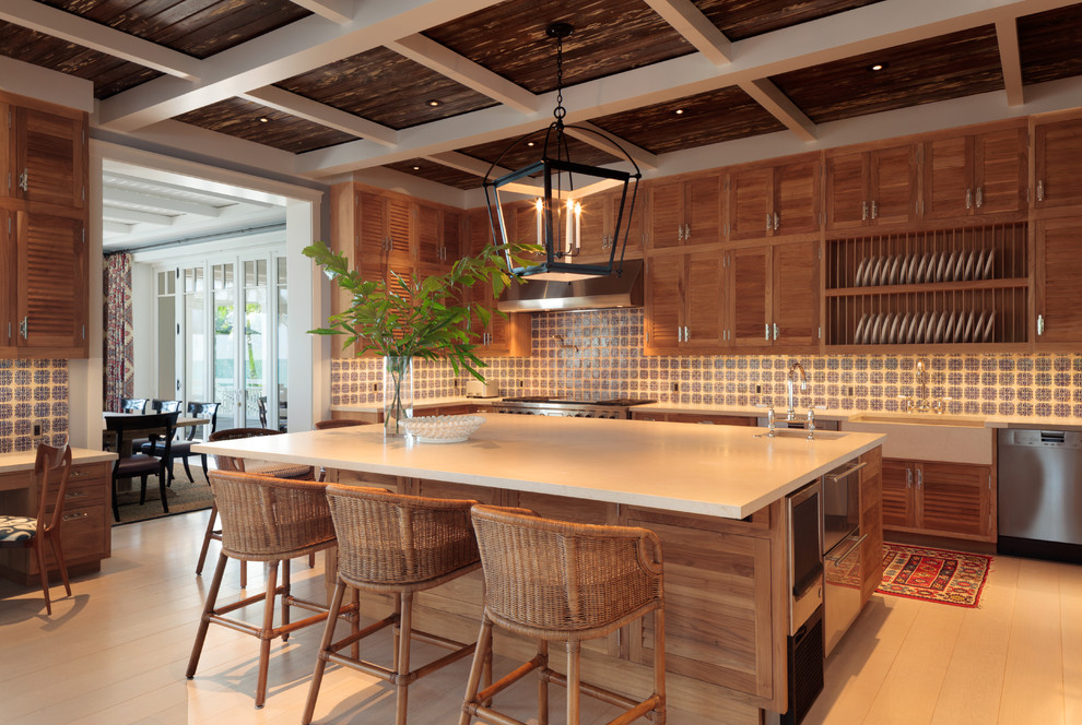 This is an example of a large beach style u-shaped eat-in kitchen in Miami with a farmhouse sink, shaker cabinets, medium wood cabinets, quartzite benchtops, blue splashback, terra-cotta splashback, stainless steel appliances, light hardwood floors and with island.