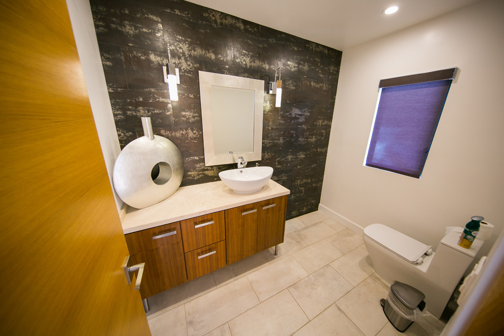 Photo of a mid-sized contemporary powder room in Los Angeles with flat-panel cabinets, medium wood cabinets, beige walls, a vessel sink, a one-piece toilet, porcelain floors, beige floor, brown tile, porcelain tile and marble benchtops.