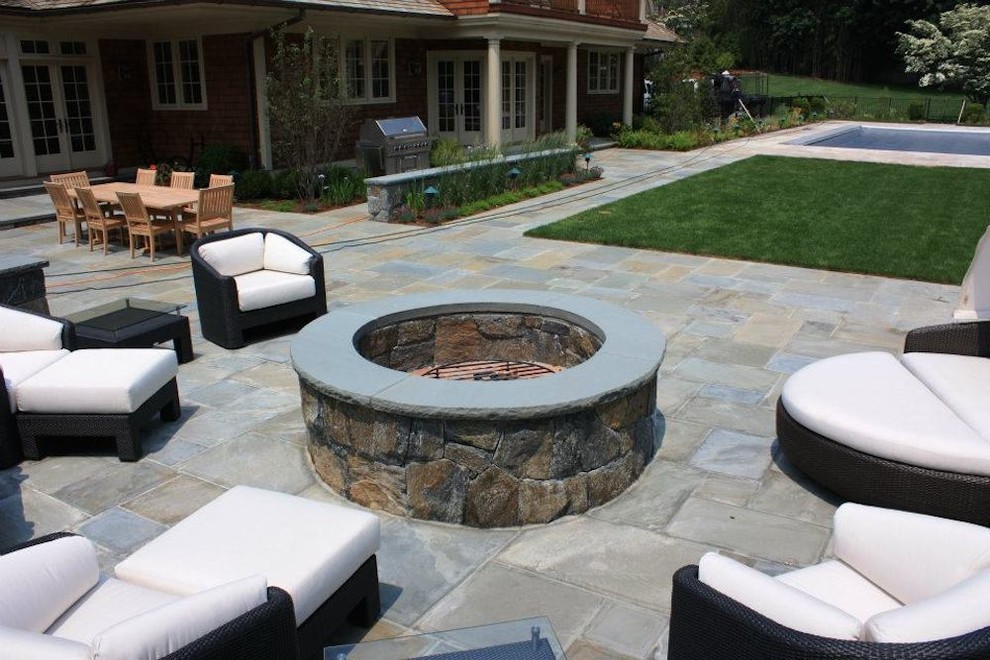 This is an example of a large traditional backyard patio in New York with a fire feature, stamped concrete and no cover.