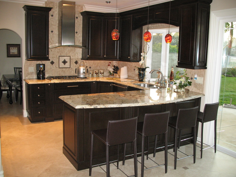 Example of a transitional u-shaped kitchen design in Orange County with a double-bowl sink, raised-panel cabinets, black cabinets, beige backsplash, stainless steel appliances and an island
