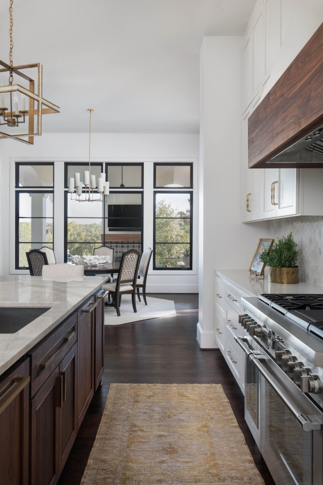Mid-sized transitional l-shaped medium tone wood floor and brown floor enclosed kitchen photo in Austin with an undermount sink, shaker cabinets, white cabinets, quartzite countertops, white backsplash, marble backsplash, stainless steel appliances, an island and beige countertops