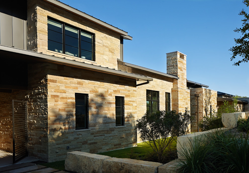 Photo of a transitional two-storey beige exterior in Austin with stone veneer.