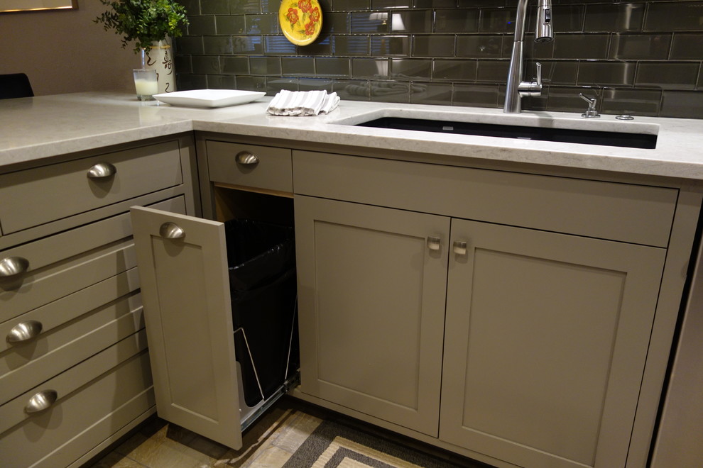 Small transitional u-shaped ceramic tile home design photo with an undermount sink, shaker cabinets, gray cabinets, quartz countertops, gray backsplash, glass tile backsplash, stainless steel appliances and a peninsula