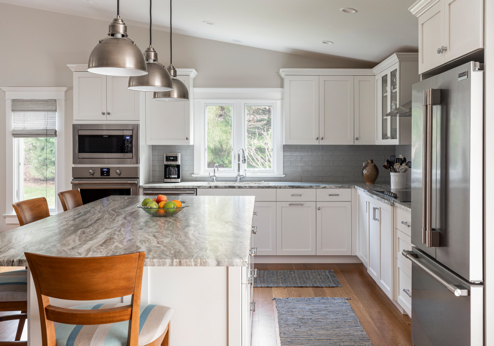 Design ideas for a large midcentury l-shaped eat-in kitchen in Providence with shaker cabinets, white cabinets, quartzite benchtops, grey splashback, glass tile splashback, stainless steel appliances, medium hardwood floors, with island and vaulted.