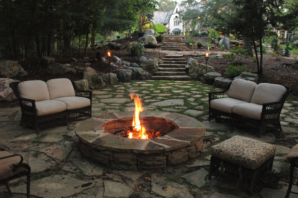 Photo of an expansive eclectic backyard patio in Cincinnati with a fire feature, natural stone pavers and no cover.