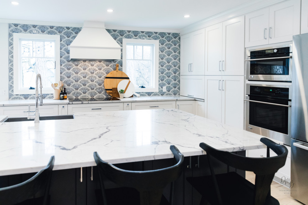 Inspiration for a transitional light wood floor and white floor kitchen remodel with a farmhouse sink, flat-panel cabinets, blue cabinets, quartz countertops, blue backsplash, glass tile backsplash, stainless steel appliances, an island and white countertops