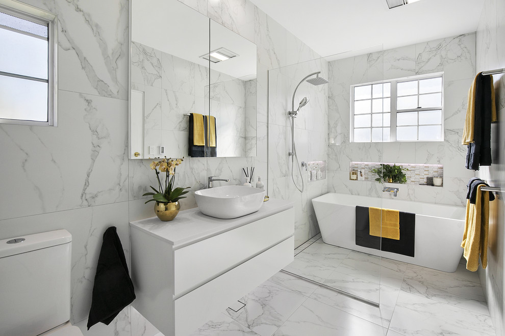 Inspiration for a large contemporary master wet room bathroom in Sydney with white cabinets, a freestanding tub, ceramic tile, white walls, ceramic floors, a vessel sink, marble benchtops, white floor, an open shower, white benchtops, flat-panel cabinets, gray tile and white tile.