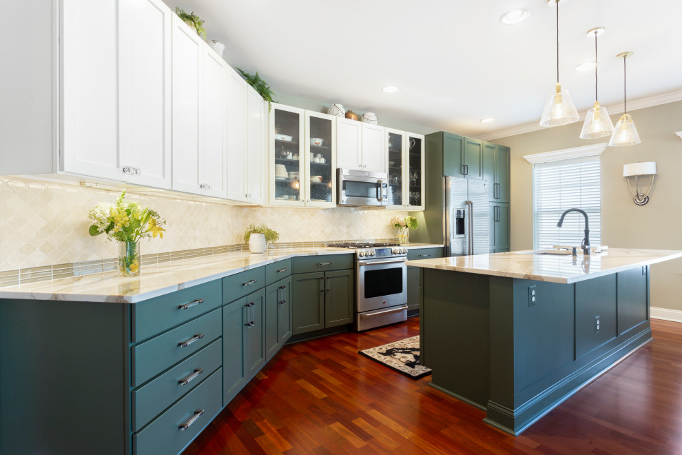 Photo of a mid-sized transitional l-shaped eat-in kitchen in Philadelphia with an undermount sink, shaker cabinets, green cabinets, solid surface benchtops, beige splashback, marble splashback, stainless steel appliances, medium hardwood floors, with island, brown floor and beige benchtop.