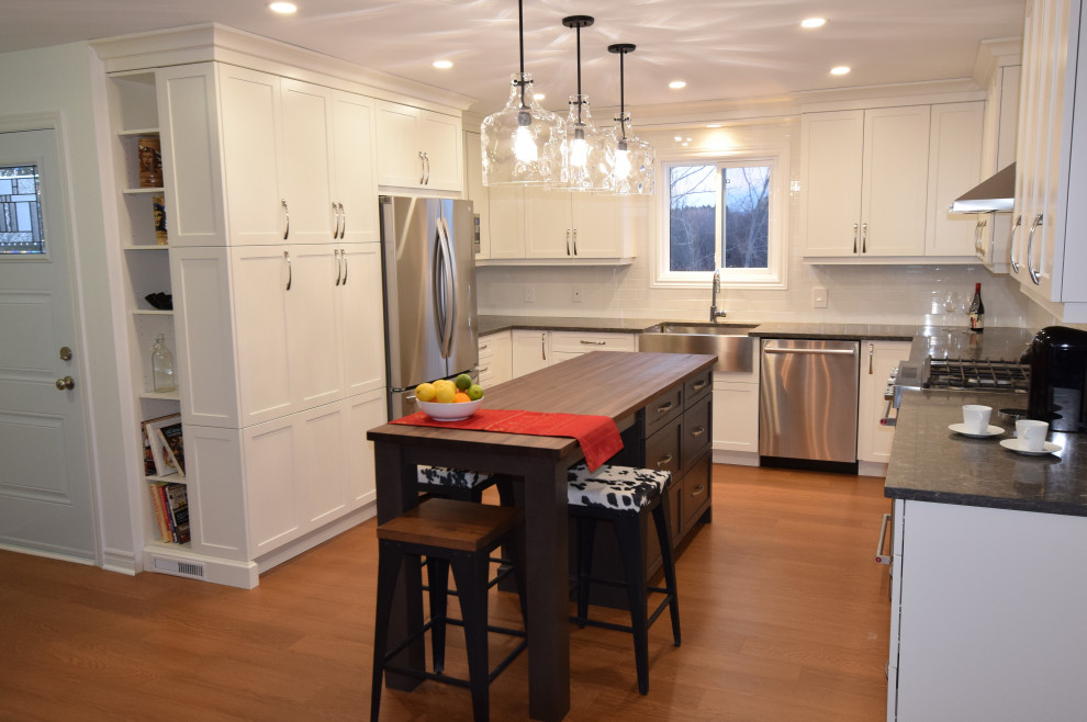 Small transitional u-shaped medium tone wood floor and brown floor open concept kitchen photo in Ottawa with a farmhouse sink, shaker cabinets, white cabinets, quartz countertops, white backsplash, subway tile backsplash, stainless steel appliances, an island and gray countertops