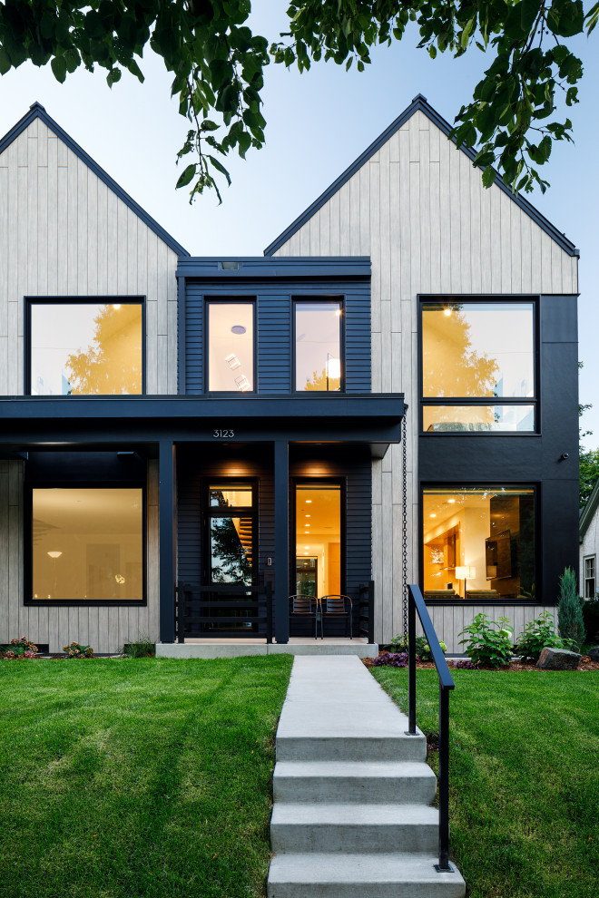 Mid-sized scandinavian two-storey beige townhouse exterior in Minneapolis with mixed siding, a gable roof, a metal roof and a black roof.