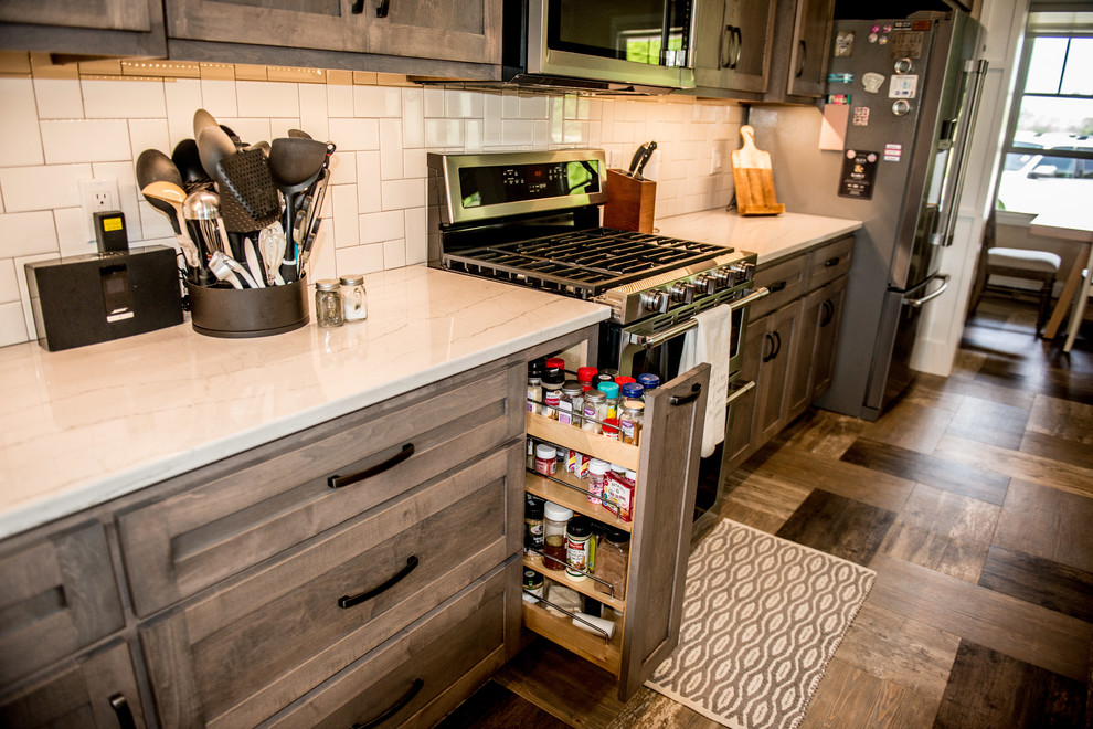 Open concept kitchen - large transitional l-shaped vinyl floor and multicolored floor open concept kitchen idea with a farmhouse sink, shaker cabinets, gray cabinets, quartz countertops, white backsplash, subway tile backsplash, stainless steel appliances, an island and white countertops