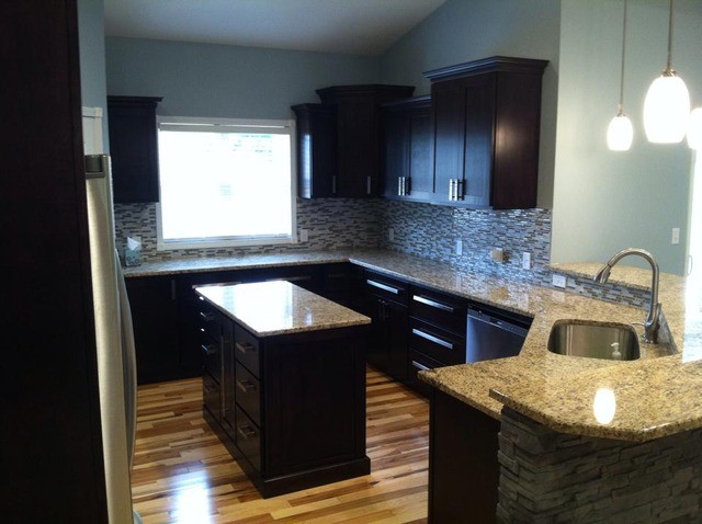 Inspiration for a large galley light wood floor enclosed kitchen remodel in Cedar Rapids with a drop-in sink, flat-panel cabinets, black cabinets, metallic backsplash and an island