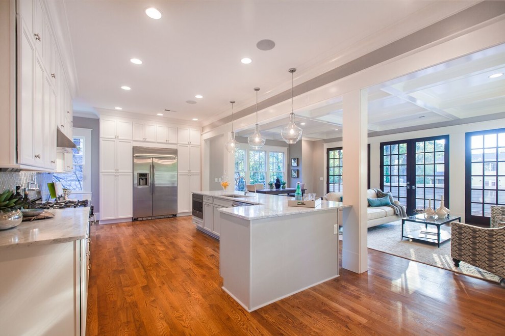 Example of a mid-sized transitional single-wall medium tone wood floor open concept kitchen design in Raleigh with a single-bowl sink, shaker cabinets, white cabinets, marble countertops, gray backsplash, stainless steel appliances and an island
