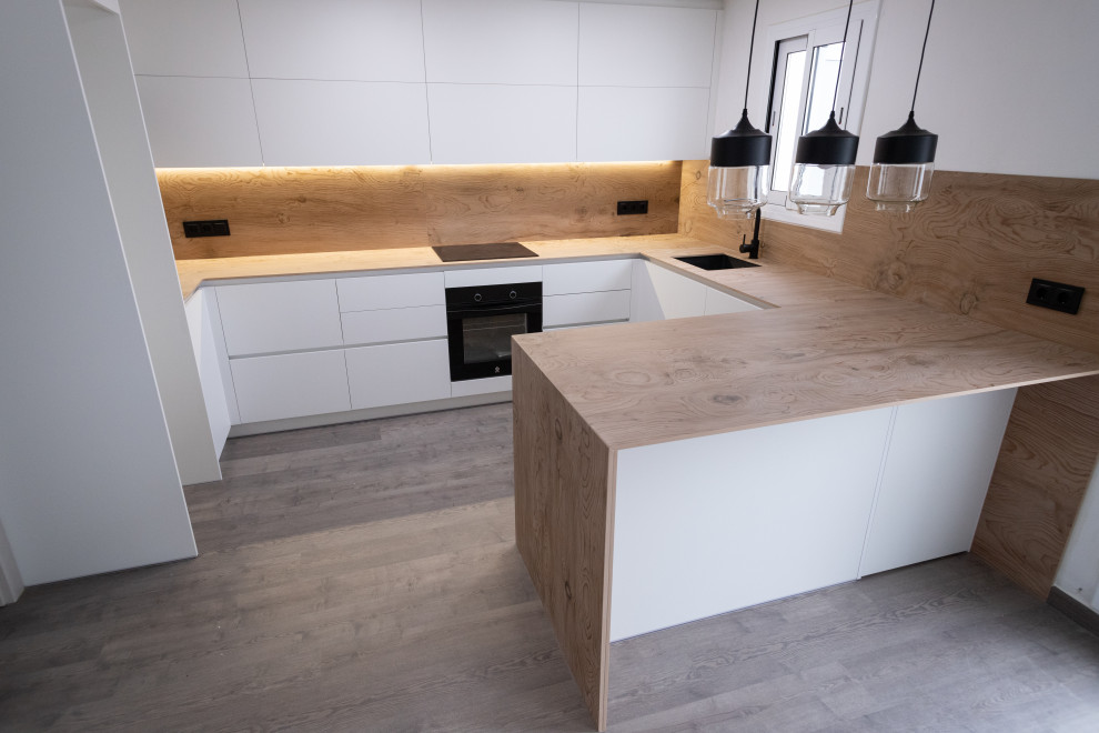 This is an example of a medium sized modern u-shaped open plan kitchen in Barcelona with a single-bowl sink, flat-panel cabinets, white cabinets, brown splashback, black appliances, ceramic flooring, no island, brown floors and brown worktops.