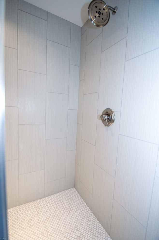 Inspiration for a mid-sized transitional 3/4 gray tile and porcelain tile porcelain tile and black floor drop-in bathtub remodel in Chicago with shaker cabinets, gray cabinets, gray walls, an undermount sink, solid surface countertops and a hinged shower door