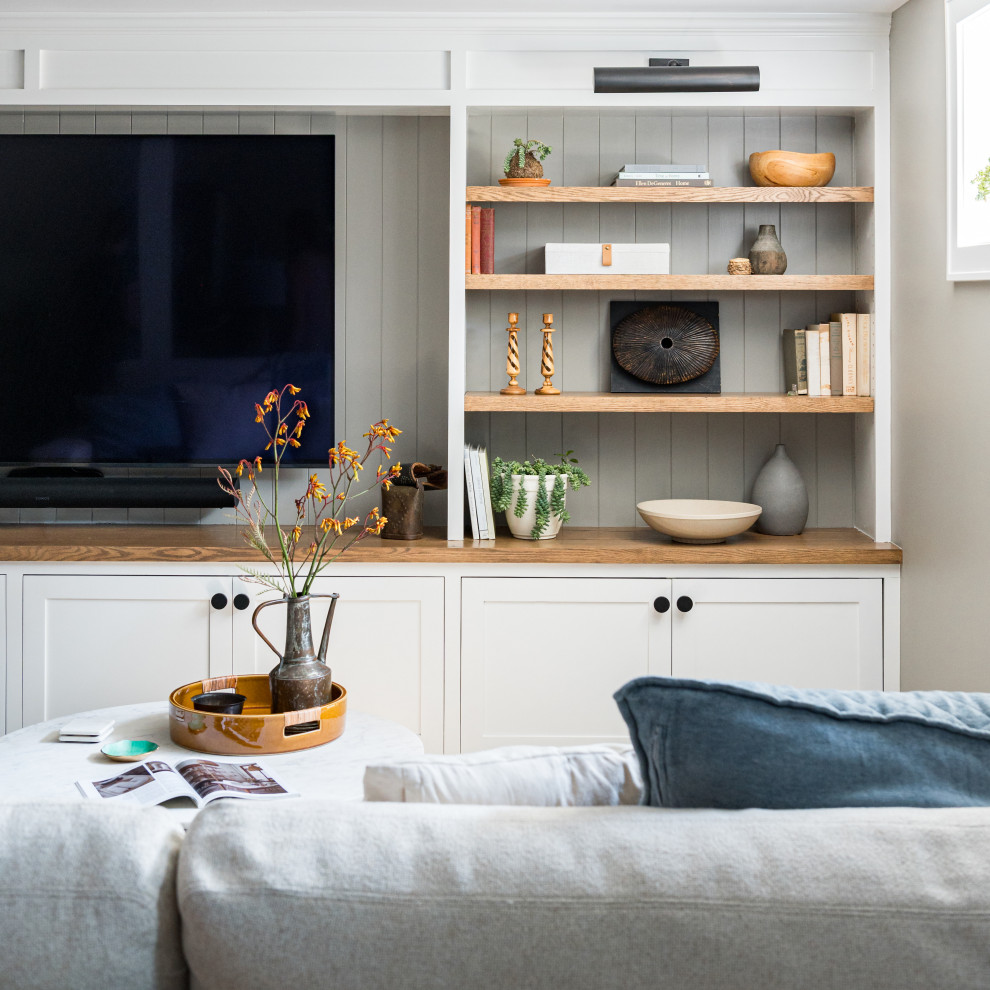 Cette image montre une salle de séjour traditionnelle de taille moyenne et fermée avec un mur gris, un téléviseur encastré et du lambris.